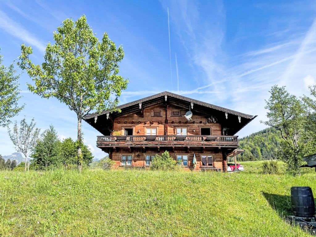 a large wooden house in a field with a tree at Holiday Home Marianne by Interhome in Reit im Winkl