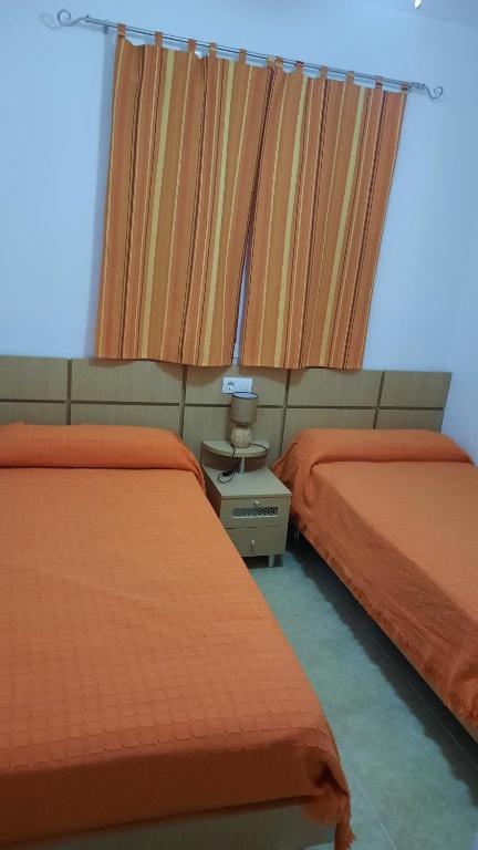 2 Betten in einem Zimmer mit orangefarbener Bettwäsche in der Unterkunft Apartamento Magic World Oropesa in Oropesa del Mar