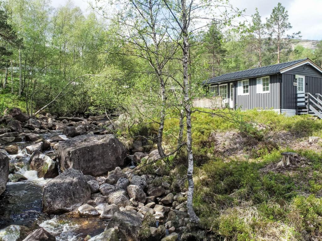 Øyuvstad的住宿－Chalet Thorabu - SOW117 by Interhome，河边树林中的小屋