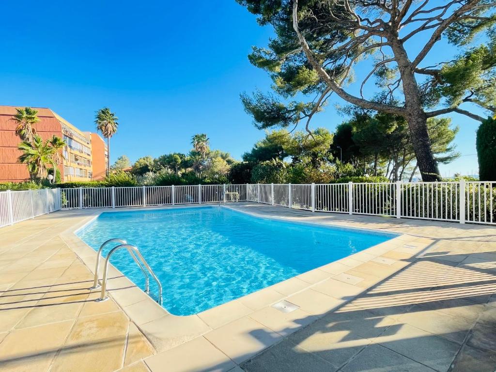 une piscine avec une clôture et un arbre dans l'établissement Appartement -piscine- proche bord de mer et centre, à Saint-Raphaël