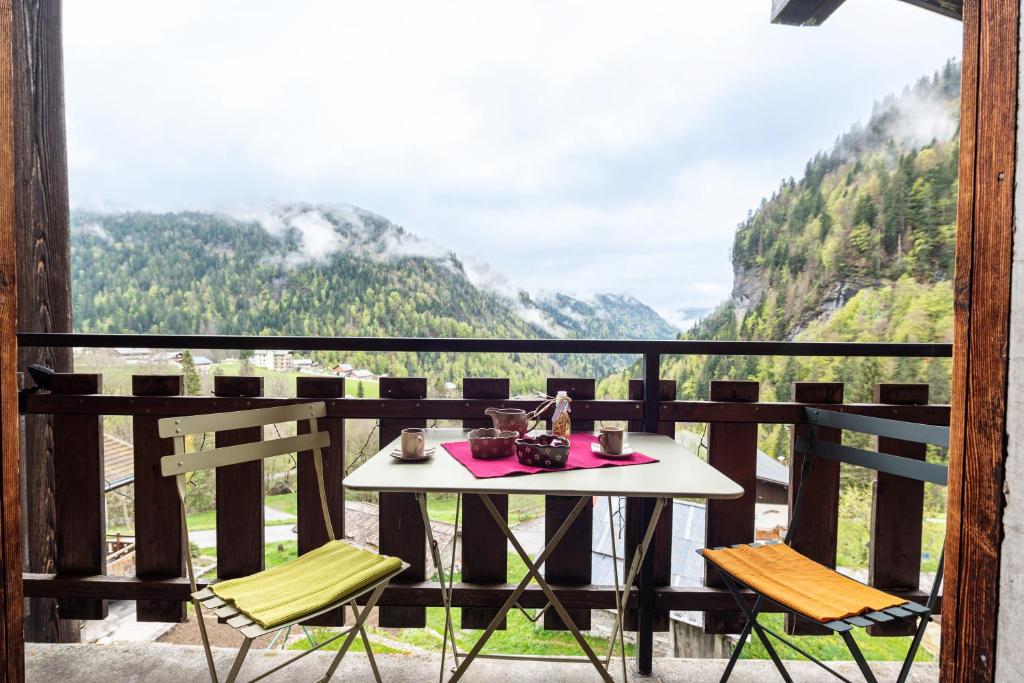 Una mesa y sillas en un balcón con vista. en Chalet Le Grand Nant, en La Giettaz