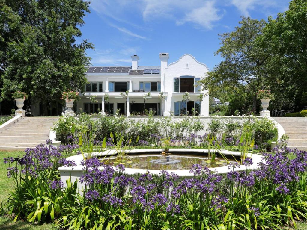 a garden with purple flowers in front of a white house at Constantia Klein in Cape Town