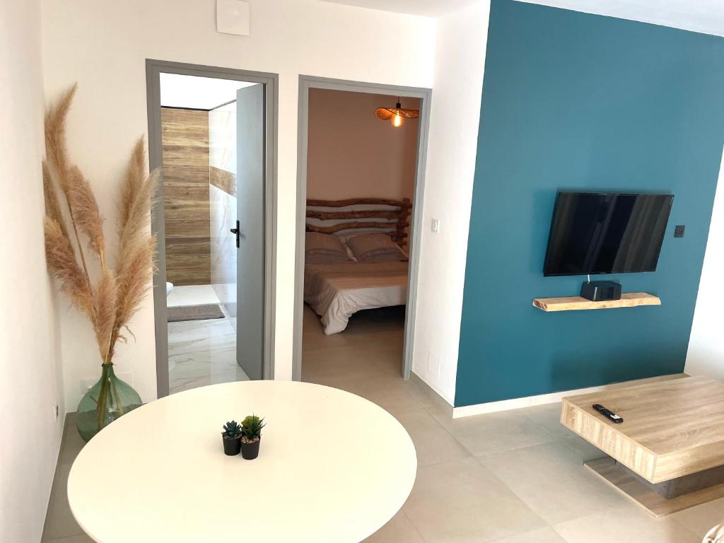 a living room with a white table and a tv at Mini maison entre mer et montagne in Aléria