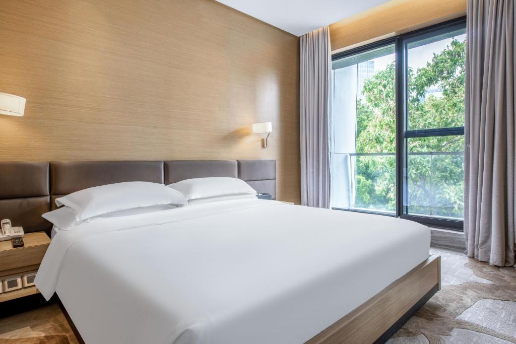 uma grande cama branca num quarto com uma grande janela em CM Serviced Apartment Shenzhen Hillside em Shenzhen