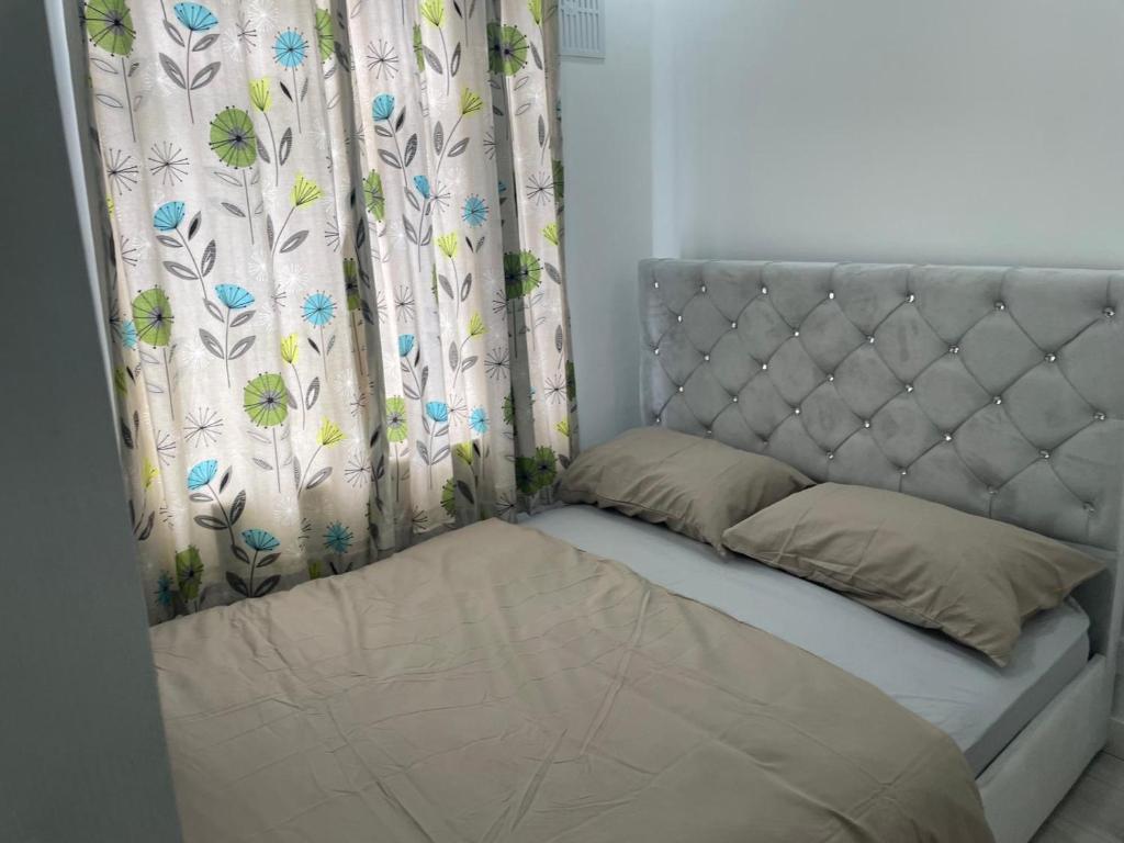 een bed in een kamer met een gordijn en een nachtrok bij Feltham rest place in Feltham