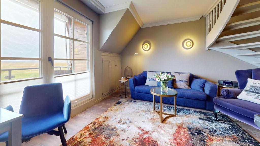 ein Wohnzimmer mit einem blauen Sofa und 2 Stühlen in der Unterkunft Wattblick in Schellinghörn