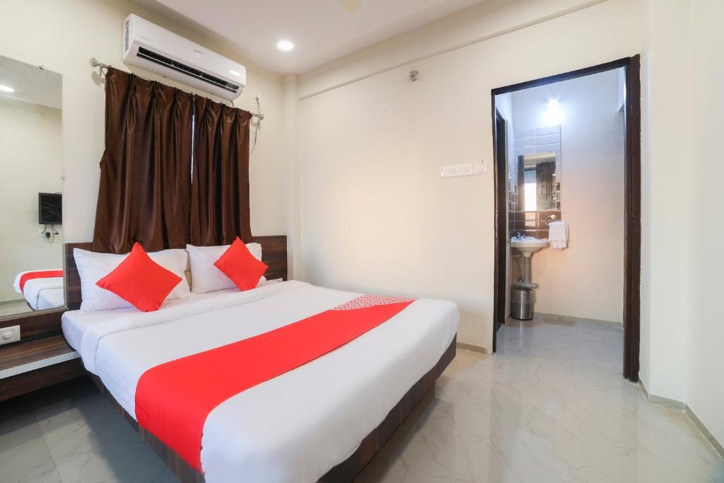 a bedroom with a large bed with red pillows at Hotel Club Metro in Dhantoli