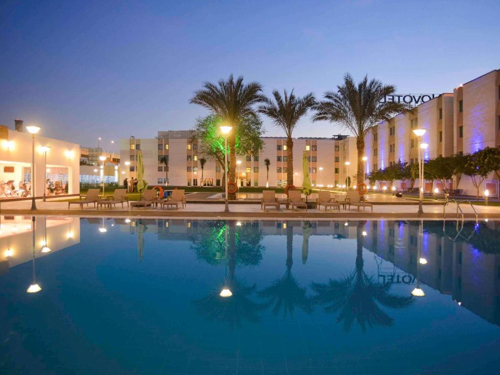 a large pool in front of a hotel at night at Novotel Cairo Airport in Cairo