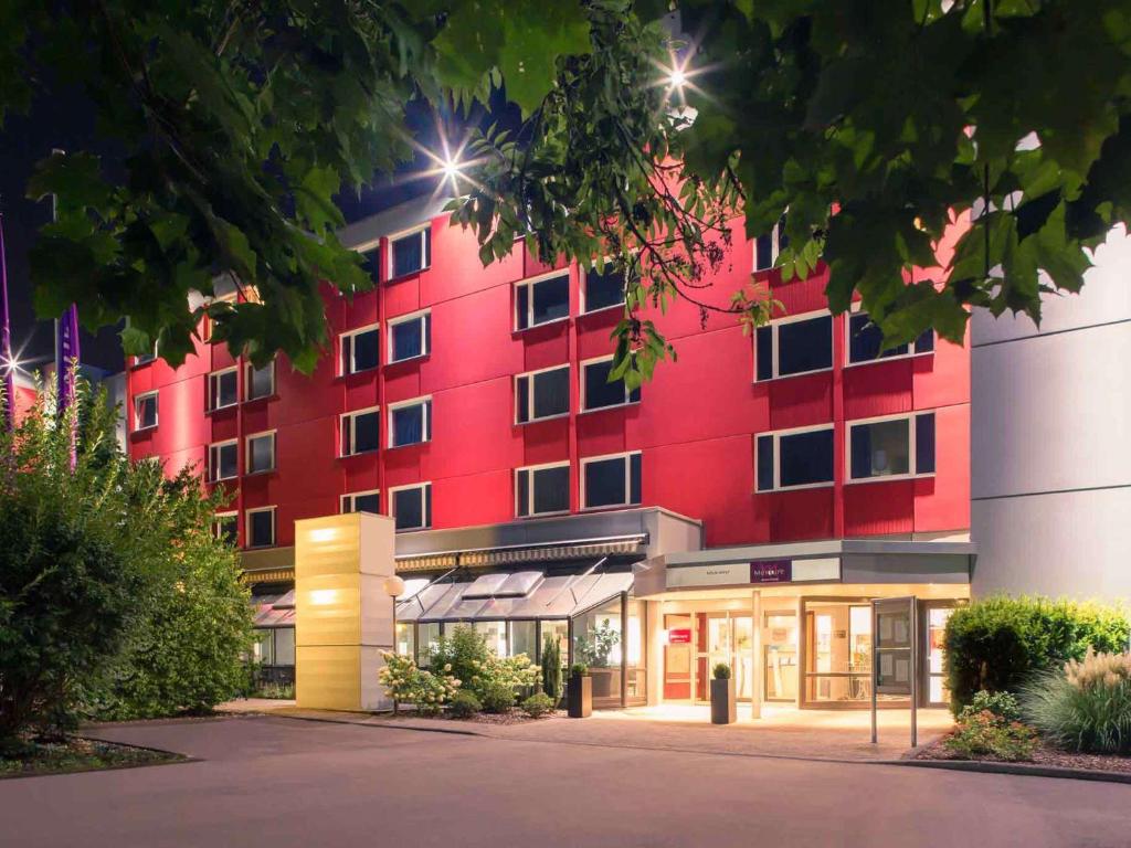 um edifício vermelho com uma loja em frente em Mercure Hotel Köln West em Colônia