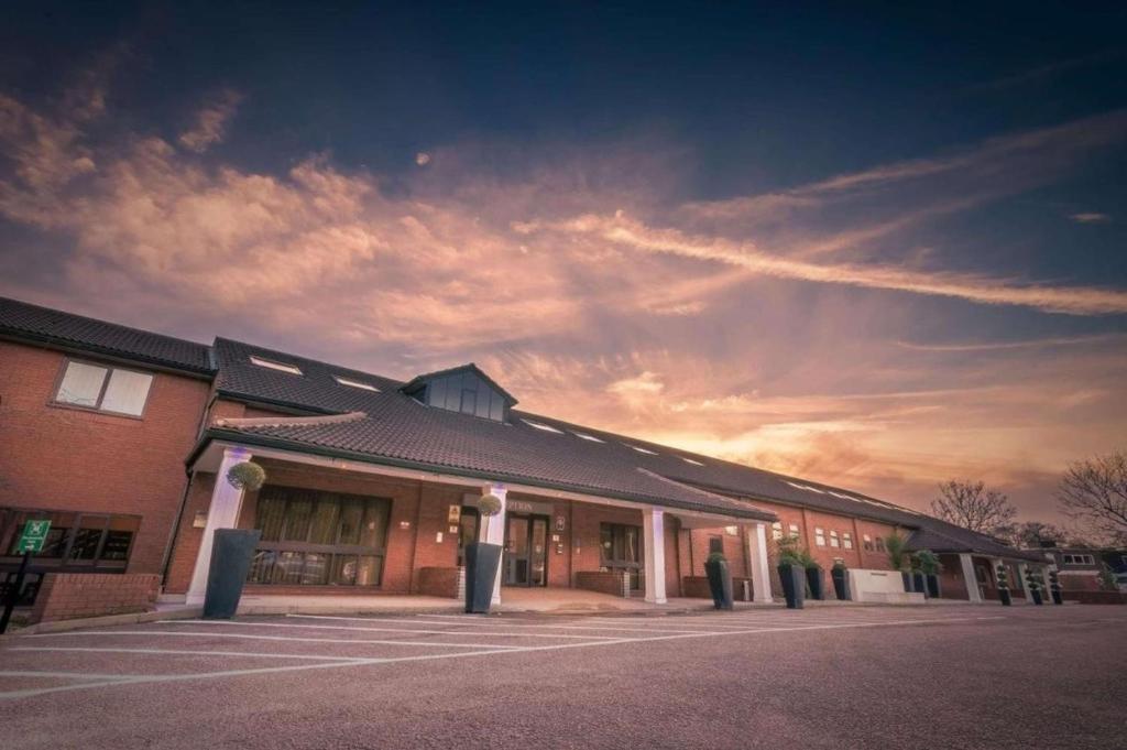 um edifício com um céu nublado à frente dele em Best Western Rockingham Forest Hotel em Corby