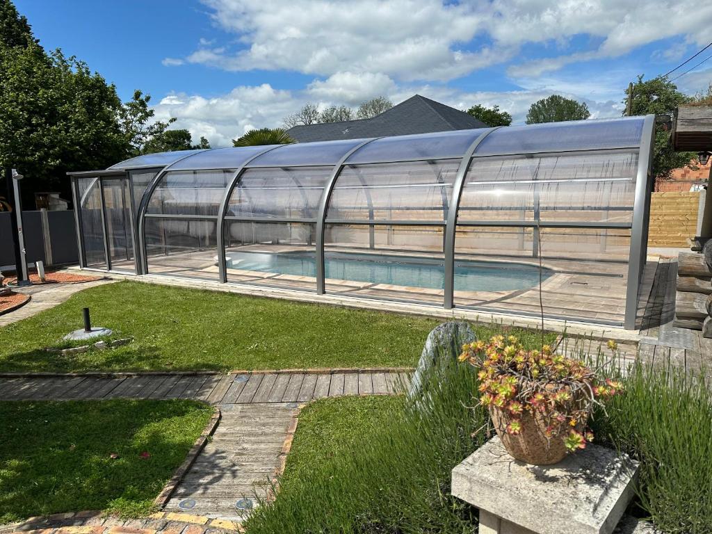 a greenhouse with a swimming pool in a yard at gite du vieux bourg in Le Vieux Bourg
