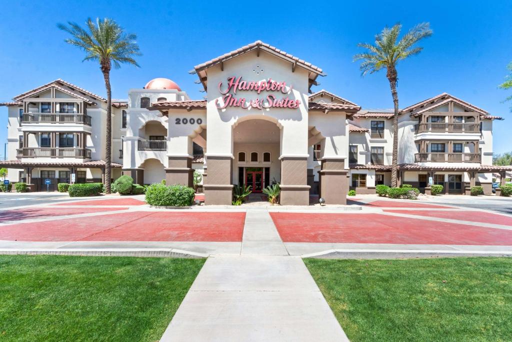 a large building with palm trees in front of it at Hampton Inn & Suites Phoenix-Goodyear in Goodyear