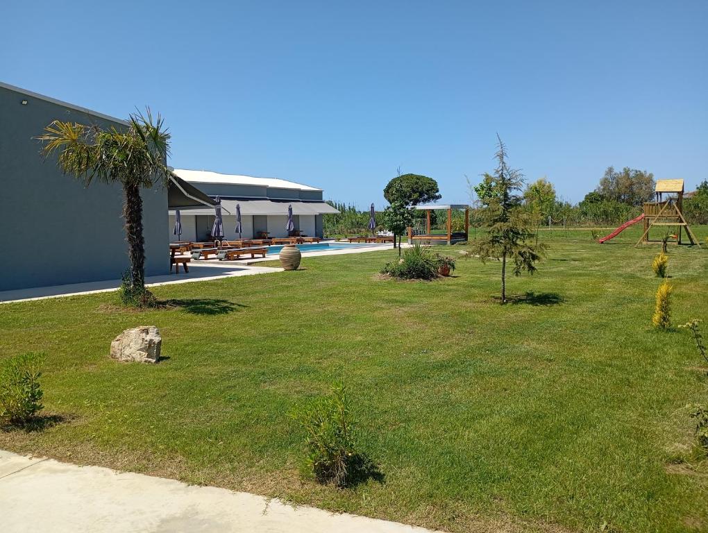 a grassy yard with a playground and a house at Olympia Suites in Pyrgos