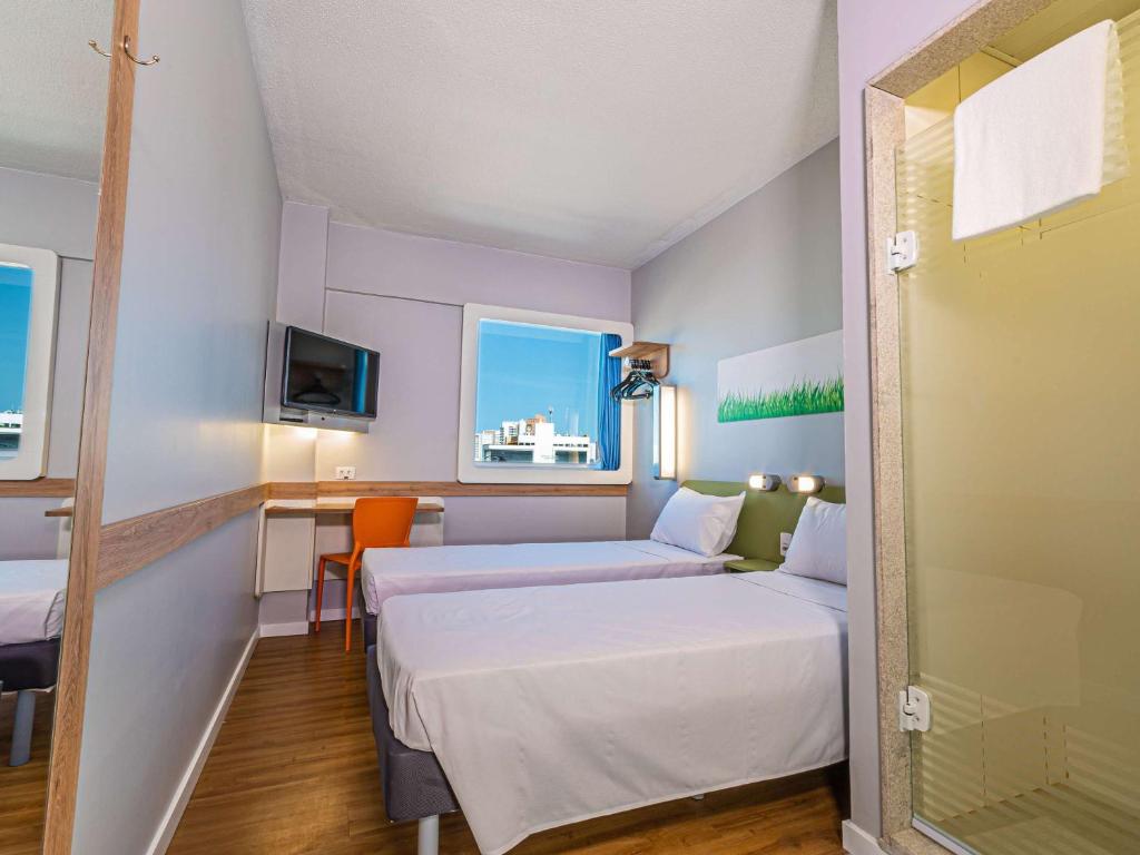 um pequeno quarto com duas camas e uma mesa em Ibis Budget Fortaleza Praia de Iracema em Fortaleza