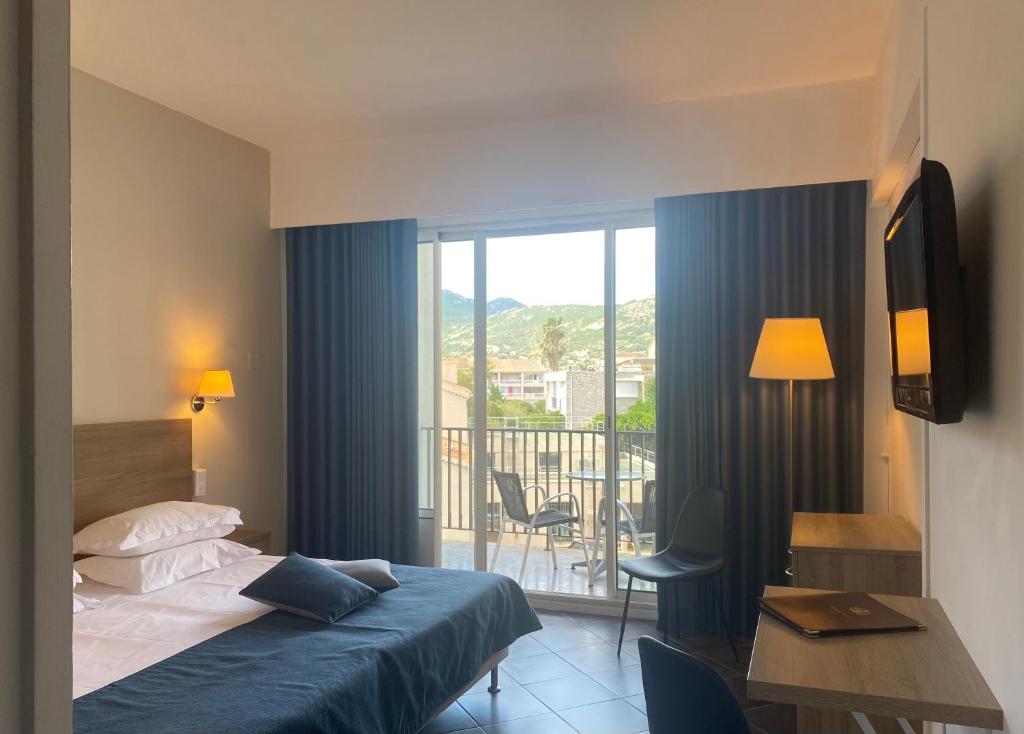 Grand Hôtel De Calvi في كالفي: غرفه فندقيه بسرير وشرفه