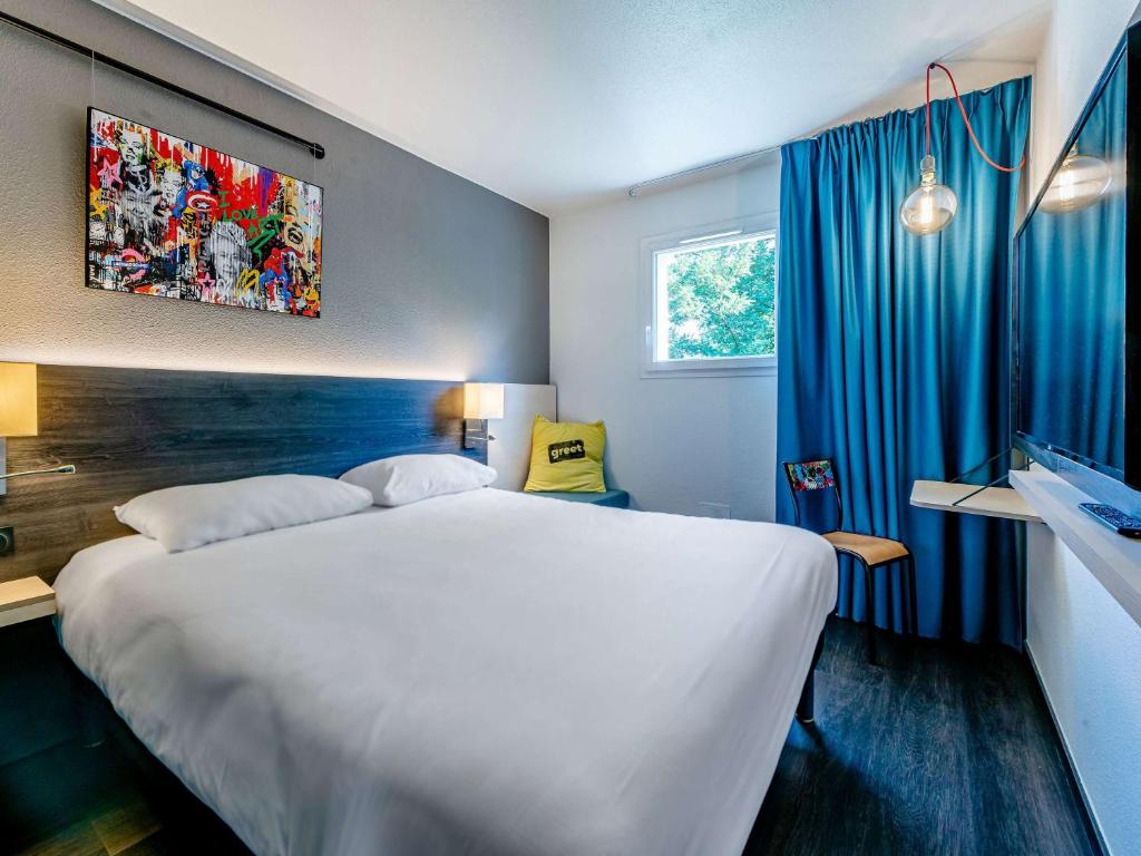 a bedroom with a large white bed and blue curtains at Greet Hotel Bordeaux Floirac Arena in Floirac