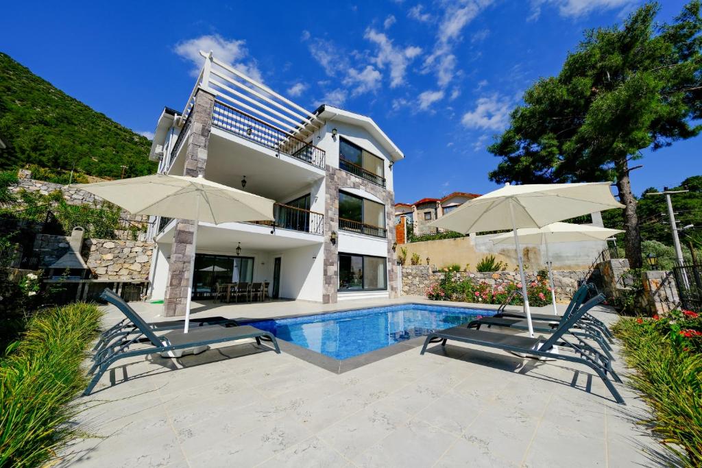 une maison avec une piscine et deux parasols dans l'établissement Oleander Hills Villa - Family-Friendly Luxury Villa Yesiluzumlu Fethiye by Sunworld Villas, à Fethiye