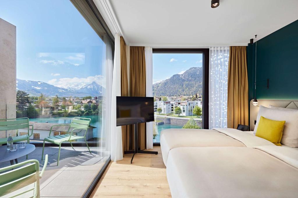 a hotel room with a bed and a large window at Essential by Dorint Interlaken - New Opening in Interlaken