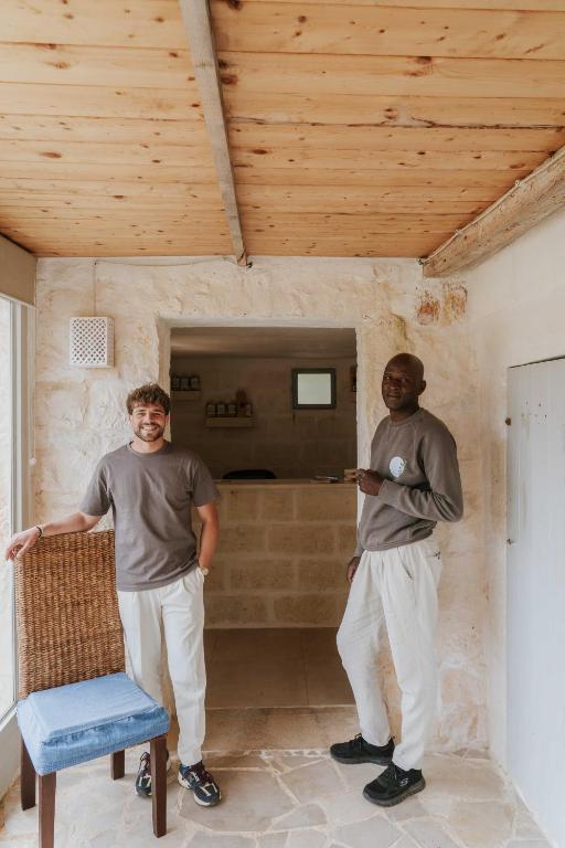 two men standing in a room with a chair at Masseria della Piana in Villanova di Ostuni
