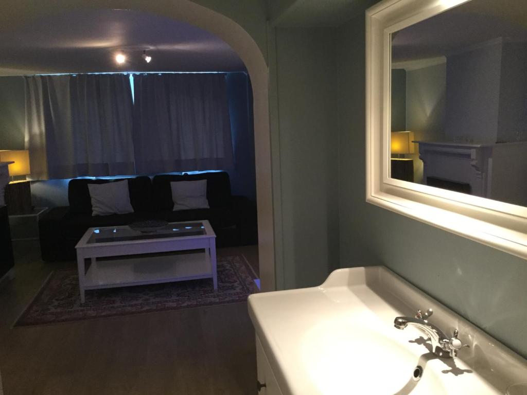 a bathroom with a sink and a living room with a couch at B&B Wellness Yoake in Ypres