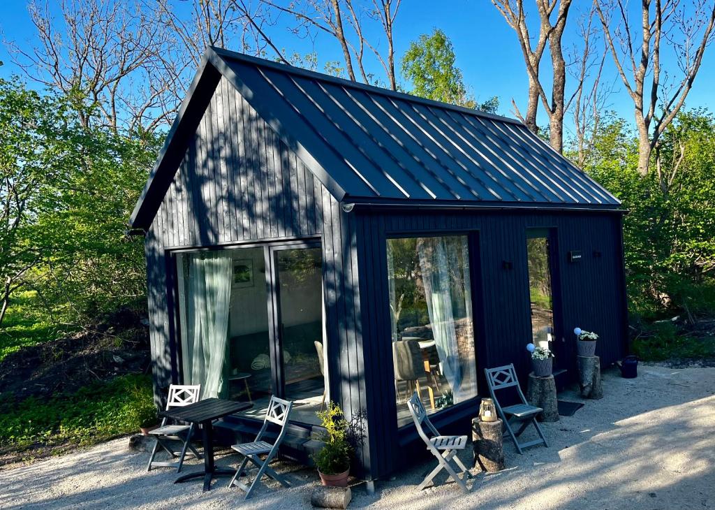 a small black shed with chairs and a table at Seaside Village House on Werder peninsula in Virtsu
