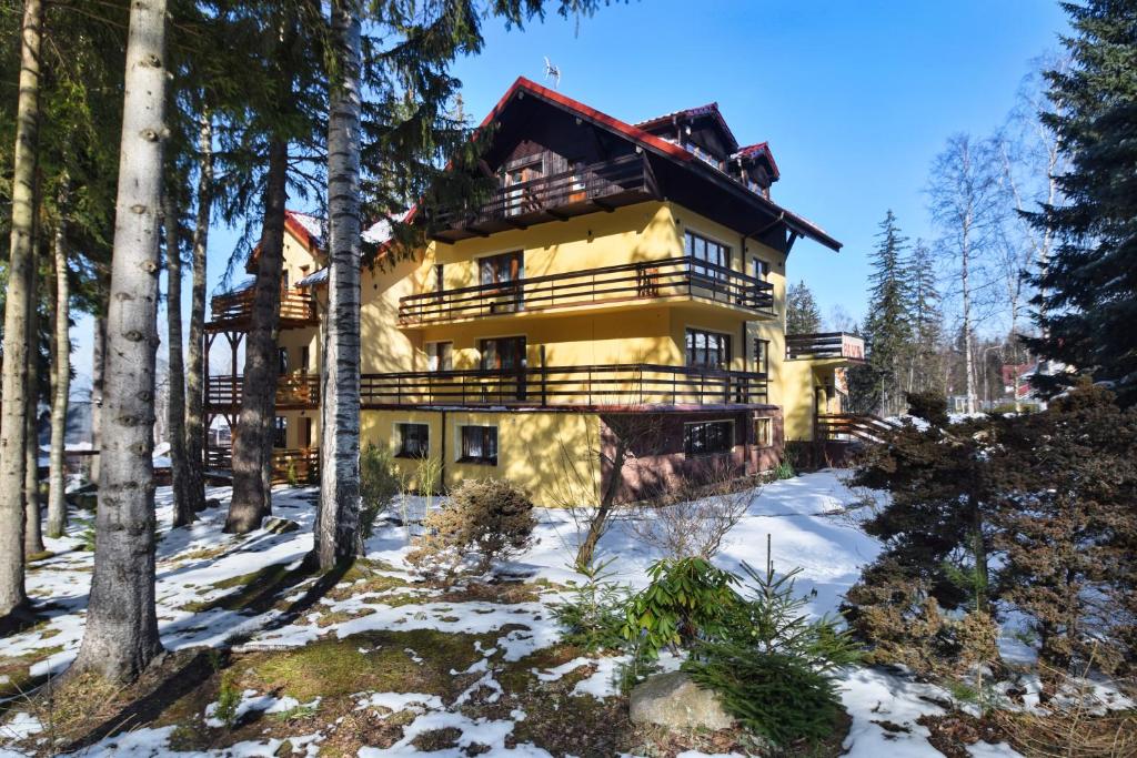 una gran casa amarilla en la nieve con árboles en Willa Paweł z balią i jacuzzi, en Karpacz