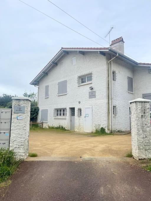 une grande maison blanche avec deux piliers de pierre devant elle dans l'établissement Appartement à 400m de la plage avec parking - CAPBRETON, à Capbreton