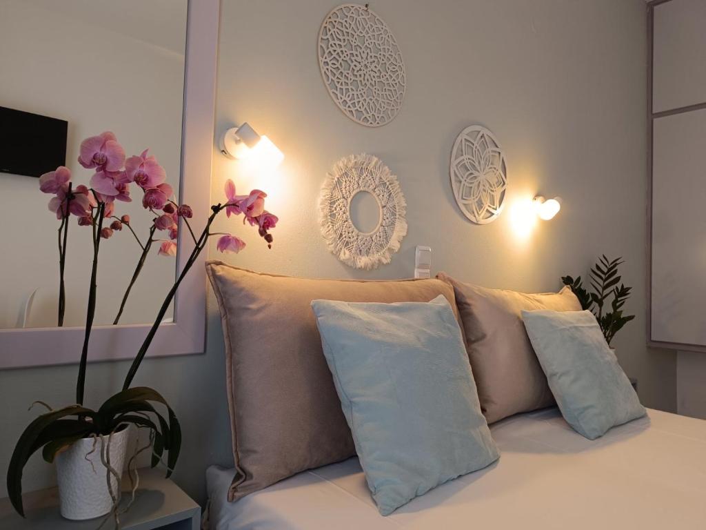 um quarto com uma cama com almofadas e um vaso com flores em Philippos Apartments em Acharavi