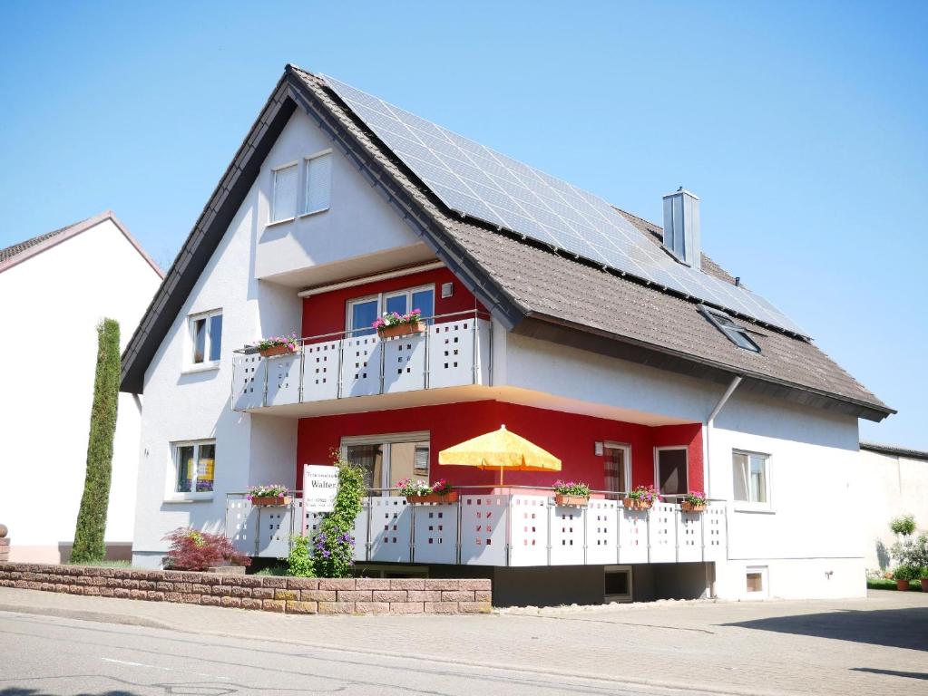 a white house with a balcony with an umbrella at Ferienwohnung Walter in Ringsheim