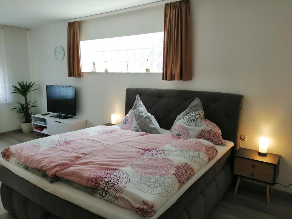 um quarto com uma cama com lençóis e almofadas cor-de-rosa em Haus Sommerberg em Titisee-Neustadt