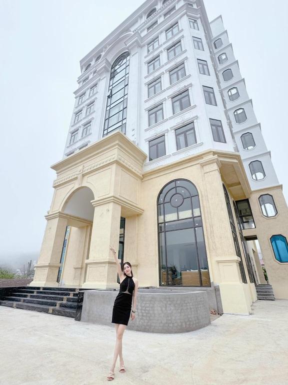 a woman in a black dress standing in front of a building at Bảo Nhi Paradise Hotel in Làng Môn