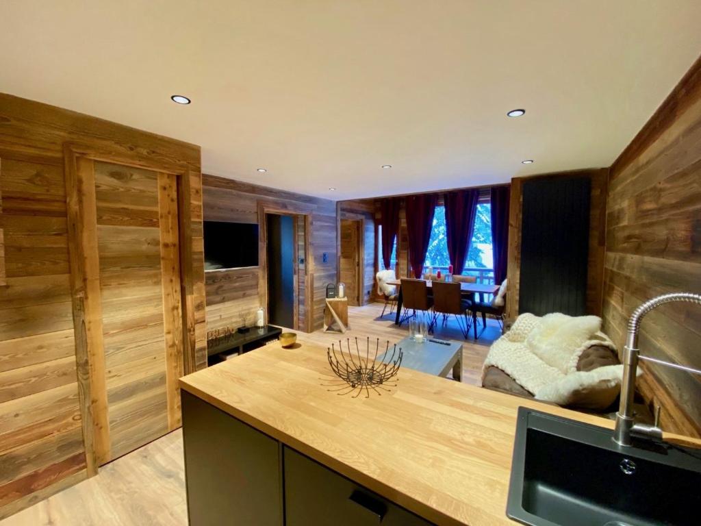 Il comprend une cuisine avec des murs en bois et un salon. dans l'établissement appartement sur les pistes, lumineux et central Courchevel 1850, à Courchevel