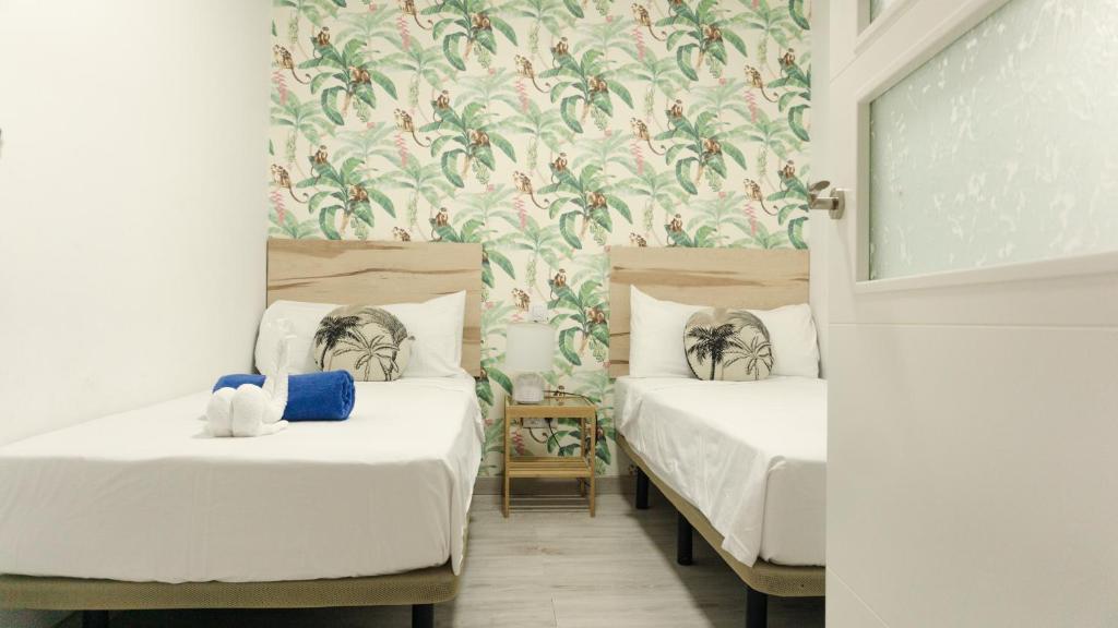 ラスパルマス・デ・グランカナリアにあるAgüita Surf Lodgeの花柄の壁紙を用いた部屋のベッド2台