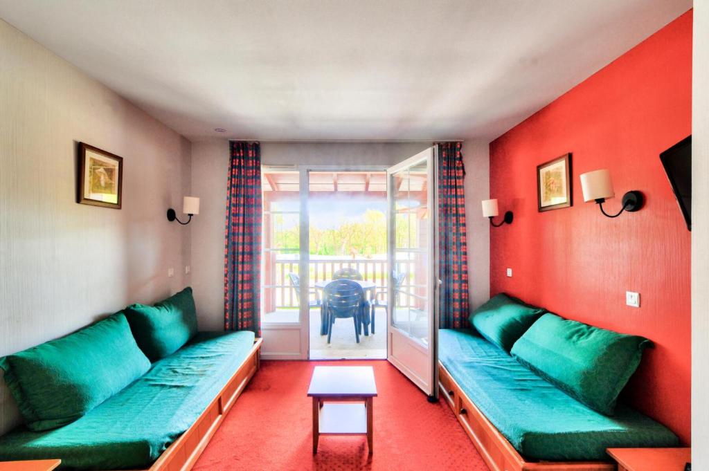 un salon avec des canapés verts et une table dans l'établissement La résidence du Lac - maeva Home - Appartement 2 pièces 5 personnes - Sélection MAE-6761, à Monflanquin