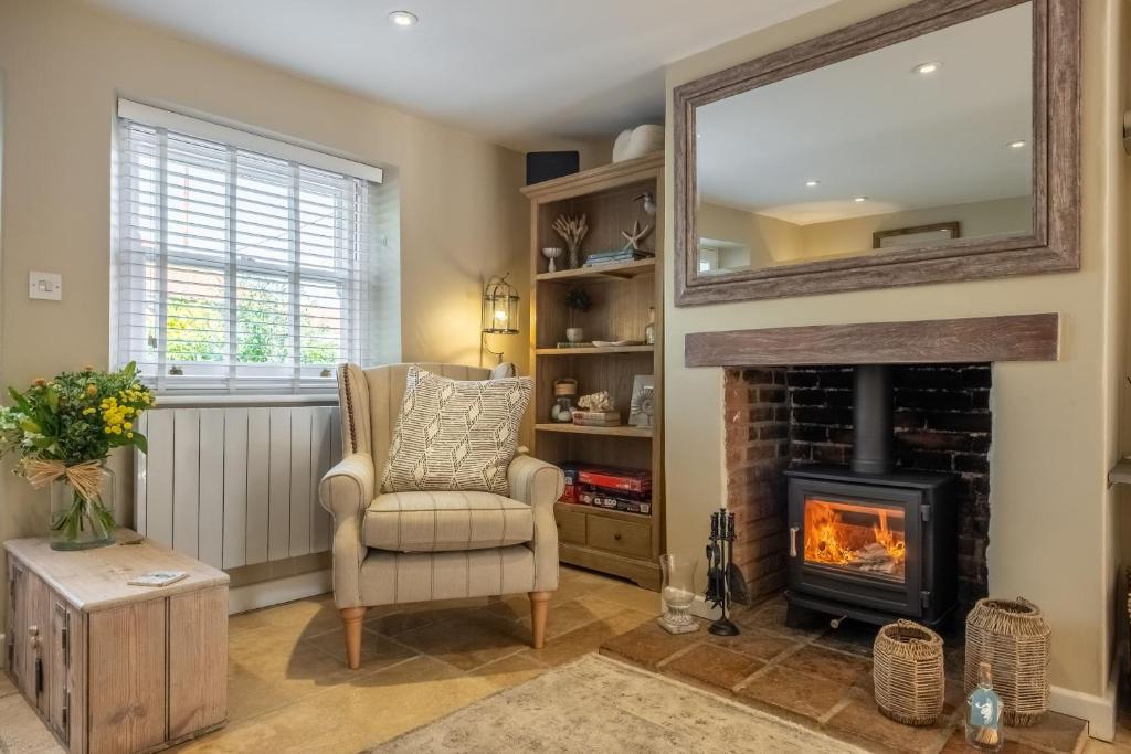 a living room with a chair and a fireplace at Charnwood Cottage 4 in Burnham Market
