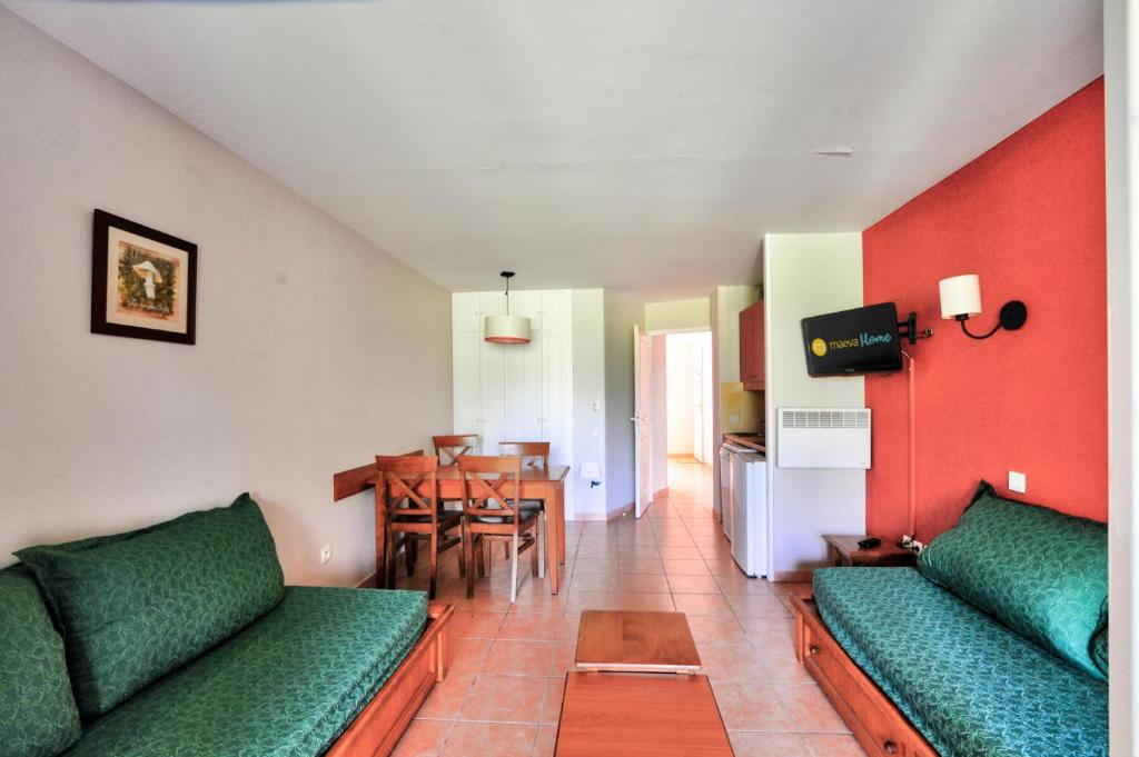 un salon avec des canapés verts et une salle à manger dans l'établissement La résidence du Lac - maeva Home - Studio 5 personnes - Sélection MAE-6771, à Monflanquin
