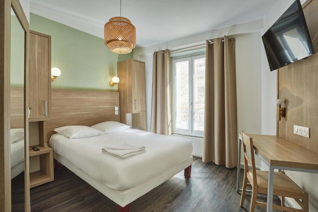 Pokój hotelowy z łóżkiem i biurkiem w obiekcie Hipotel Paris Gare du Nord Merryl w Paryżu