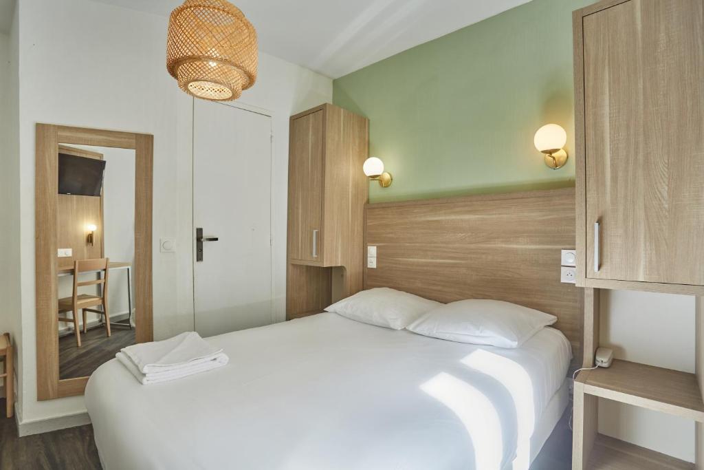 1 dormitorio con 1 cama blanca grande y espejo en Hipotel Paris Gare du Nord Merryl en París