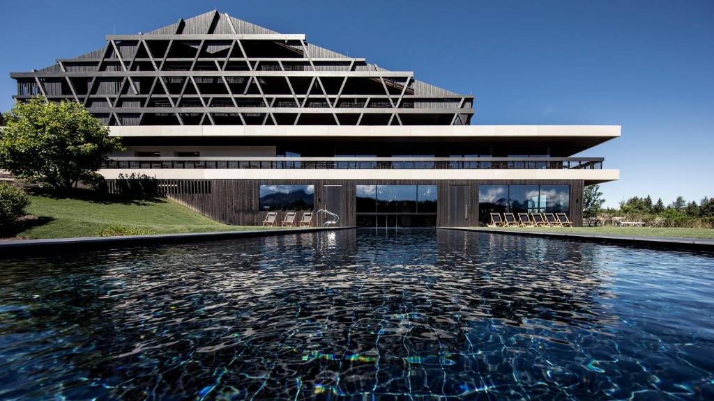 um edifício com uma piscina de água em frente em Naturhotel Pfösl em Nova Ponente