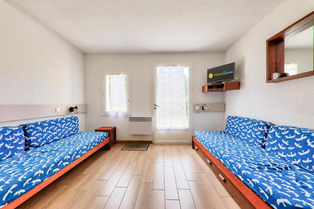 une chambre avec deux canapés bleus et deux fenêtres dans l'établissement Résidence Port du Crouesty - maeva Home - Appartement 2 pièces 4 personnes - Budget MAE-9831, à Arzon