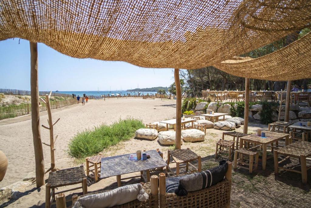 una playa con mesas y sillas en la arena en Le Domaine de la mer - Beach hotel Nature&Authenticité Hyères en Hyères