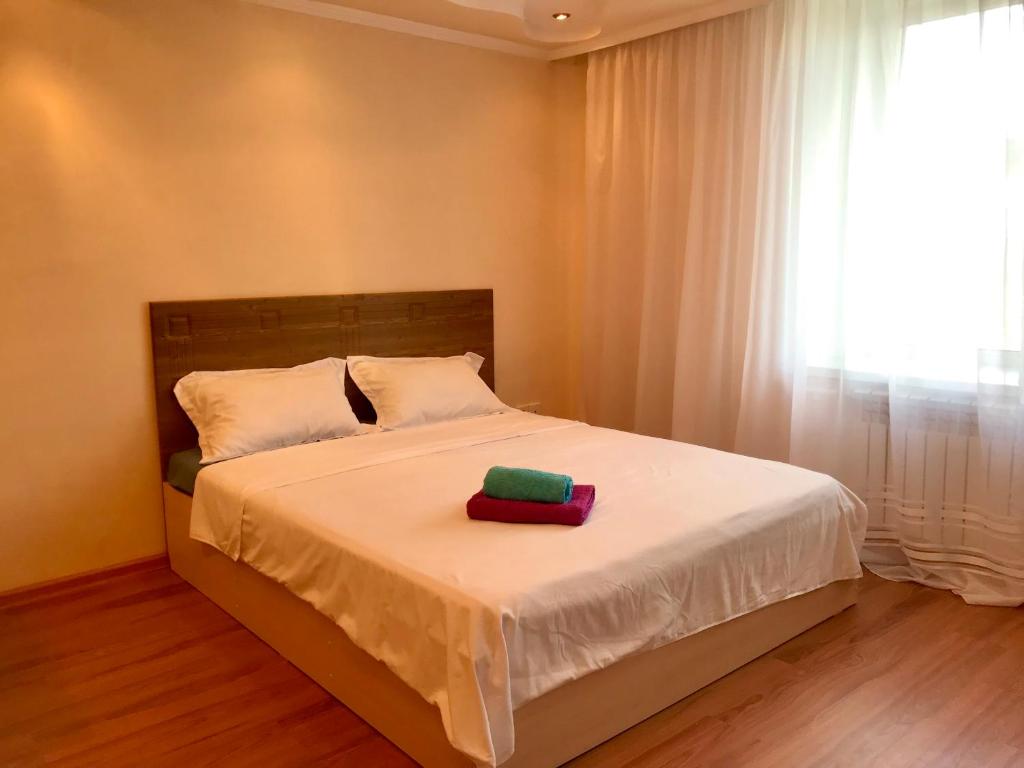 a bedroom with a bed with white sheets and a window at City Center - Nurken Abdirova 32 in Karagandy