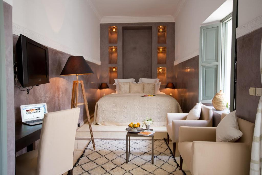 une chambre avec un lit, une table et des chaises dans l'établissement Riad Olema et Spa, à Marrakech