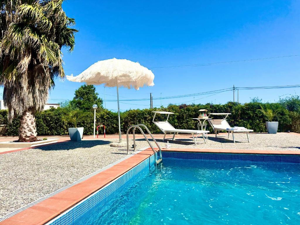a swimming pool with an umbrella and a table and chairs at Il mare di Ognina in Siracusa