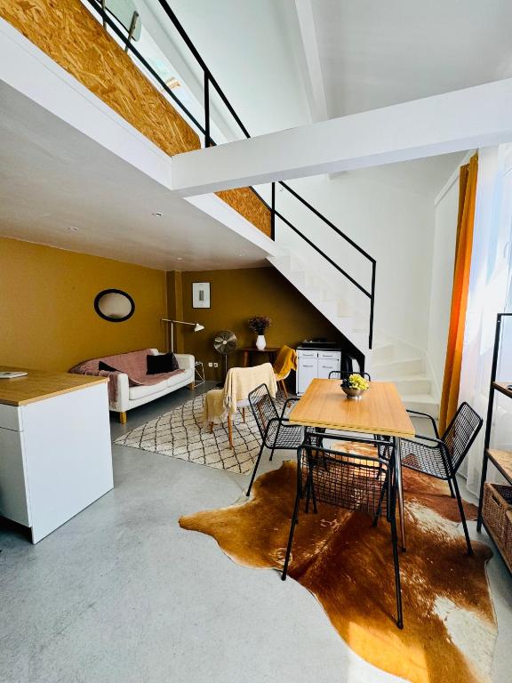 un salon avec une table et un escalier dans l'établissement Charmant duplex centre ville, à Pantin
