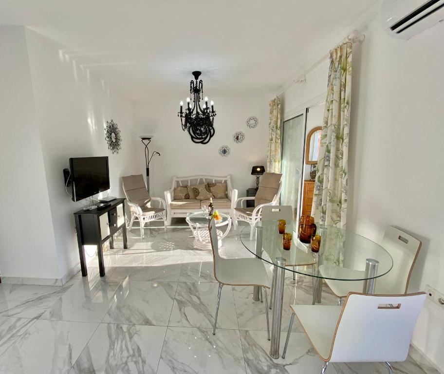 SHR043 Nerja Medina Apartamento cerca de Playa Torrecilla في نيرخا: غرفة معيشة مع طاولة وكراسي زجاجية