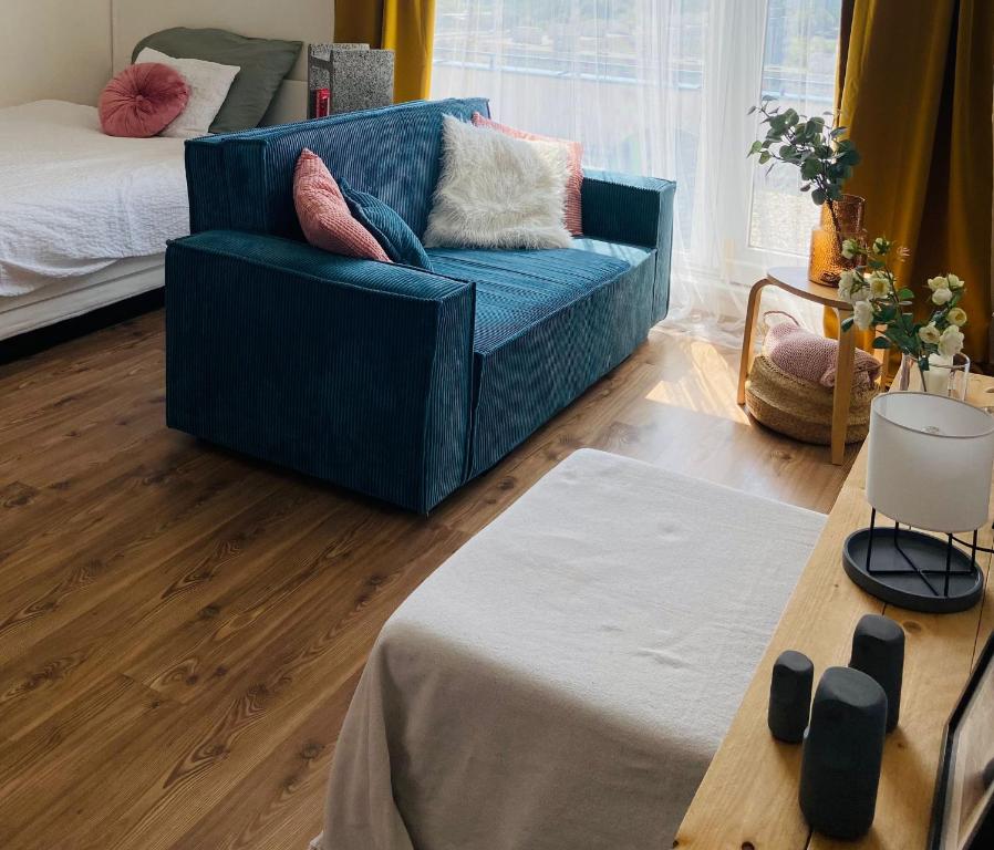 a living room with a blue couch and a bed at Cozy studio on the roof, next to Incheba Expo in Bratislava