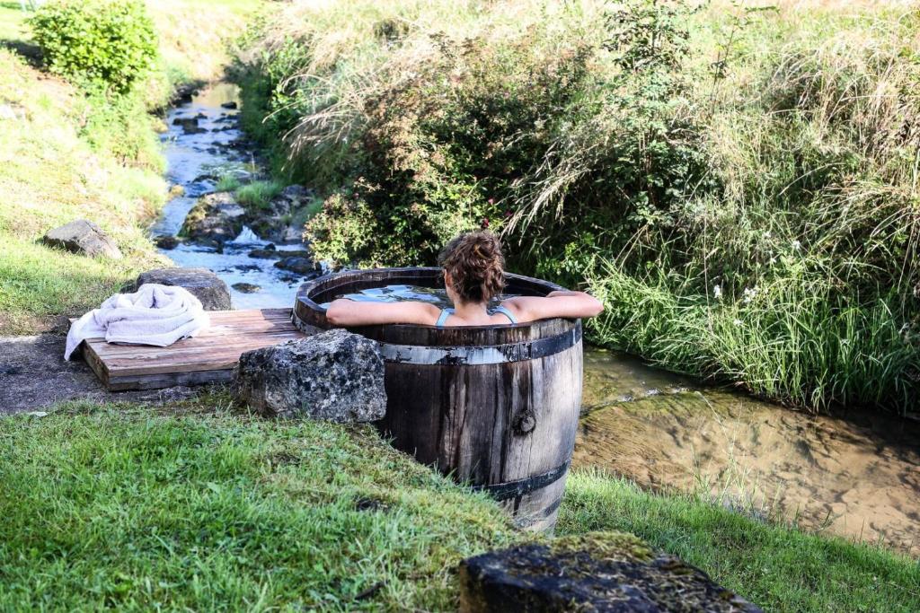 Bains de Secours, Chambres d'hotes في Sévignacq-Meyracq: امرأة جالسة في حوض الاستحمام بجوار تيار