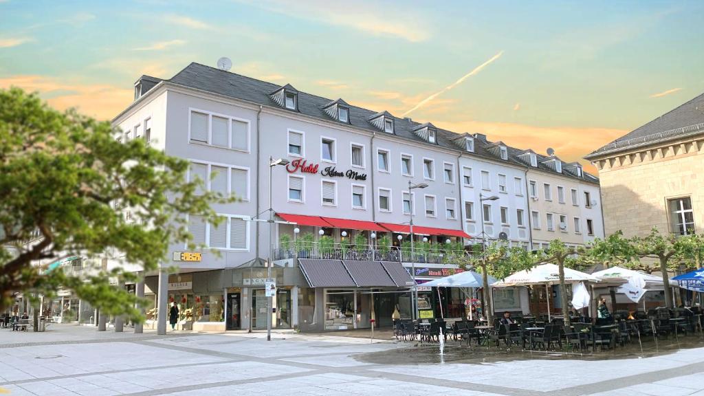 a large white building with tables and chairs on a street at Hotel Kleiner Markt in Saarlouis