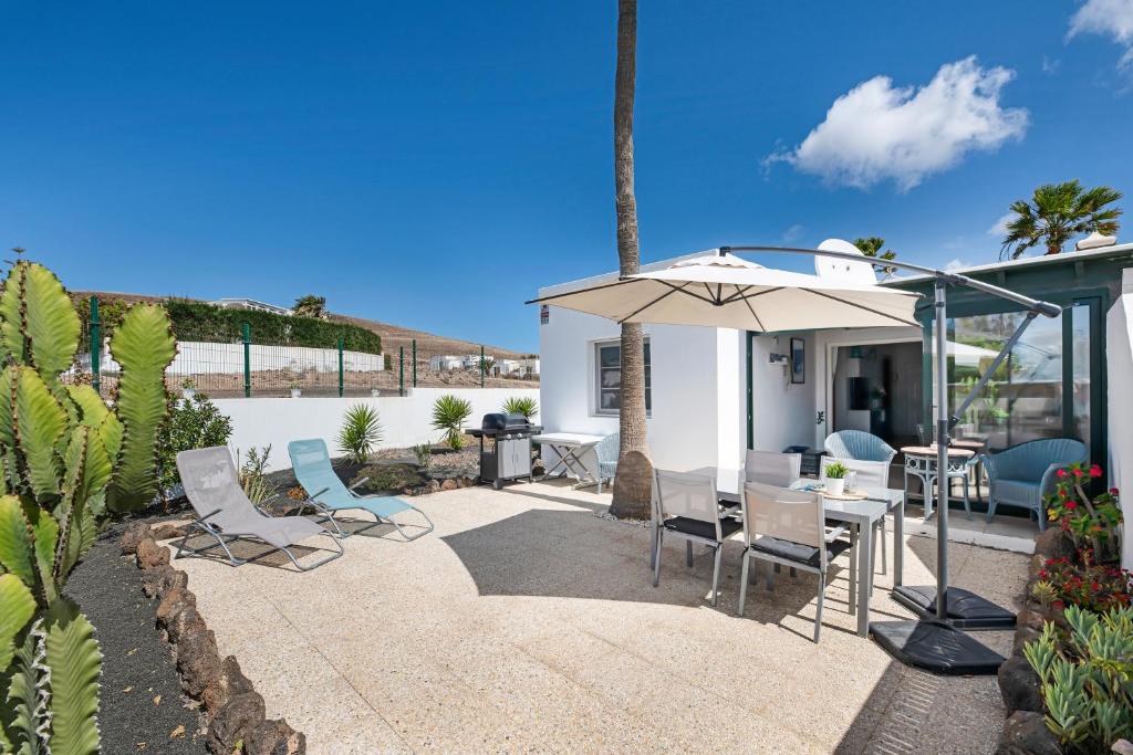 eine Terrasse mit einem Tisch, Stühlen und einem Sonnenschirm in der Unterkunft Mi Casita in Playa Blanca